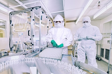 Travailleurs de laboratoire portant des tenues aseptiques avec des combinaisons jetables